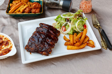 BBQ Grilled pork ribs and potato fries with barbecue sauce and ketchup and grilled vegetables