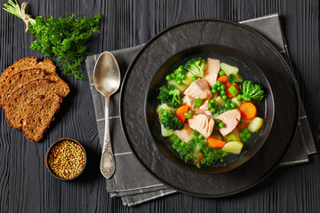 salmon, veggies and green herbs soup in bowl