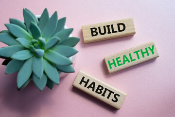Healthy habits symbol. Concept word Build Healthy habits on wooden blocks. Beautiful pink...