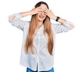 Beautiful caucasian woman wearing casual white shirt covering eyes with hands smiling cheerful and funny. blind concept.