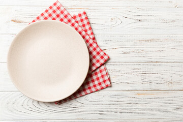 Top view on colored background empty round white plate on tablecloth for food. Empty dish on napkin...