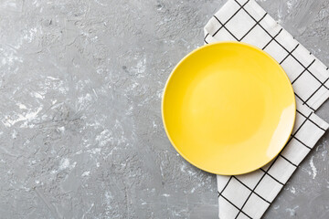 Top view on colored background empty round yellow plate on tablecloth for food. Empty dish on...