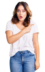 Fototapeta premium Young beautiful caucasian woman wearing casual white tshirt surprised pointing with finger to the side, open mouth amazed expression.