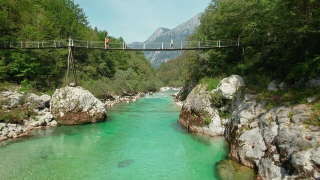 A suspension bridge spans the emerald waters of the Soca River in Slovenia