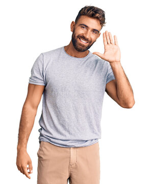 Young hispanic man wearing casual clothes waiving saying hello happy and smiling, friendly welcome gesture