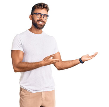 Young hispanic man wearing casual clothes and glasses inviting to enter smiling natural with open hand