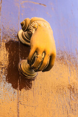 Bright doorknocker with hand shape on old wooden door