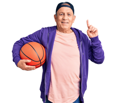 Senior handsome grey-haired man holding basketball ball surprised with an idea or question pointing finger with happy face, number one