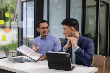 Two Asian businessmen discuss pitching startup ideas, brainstorming ideas, analyzing and planning for business success.
