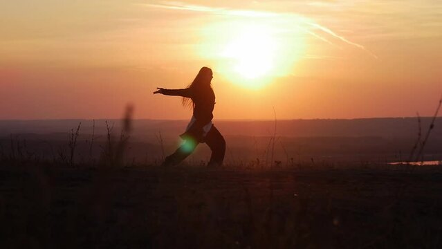 A girl dancing at sunset among the hills