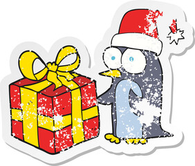 retro distressed sticker of a cartoon christmas penguin with present