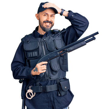 Young handsome man wearing police uniform holding shotgun stressed and frustrated with hand on head, surprised and angry face