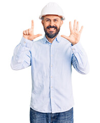 Young handsome man wearing architect hardhat showing and pointing up with fingers number seven while smiling confident and happy.