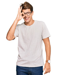 Handsome caucasian man wearing casual clothes and glasses doing ok gesture with hand smiling, eye looking through fingers with happy face.