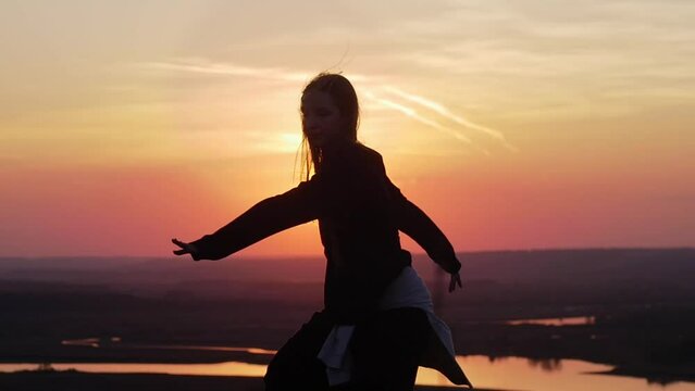 A girl dancing on a hill by the river