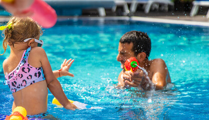 A child and his father play with a water pistol in the water. Selective focus.