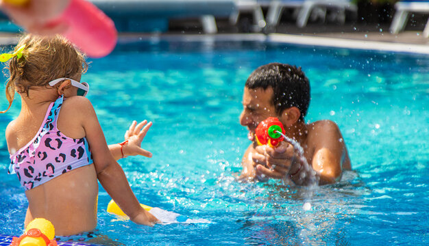 A child and his father play with a water pistol in the water. Selective focus.