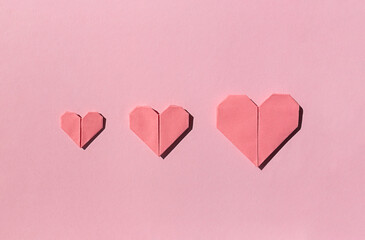 Pink paper origami hearts on the pink background. Valentine's day celebration concept