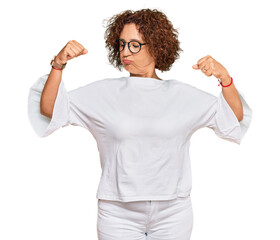 Beautiful middle age mature woman wearing casual clothes and glasses showing arms muscles smiling proud. fitness concept.