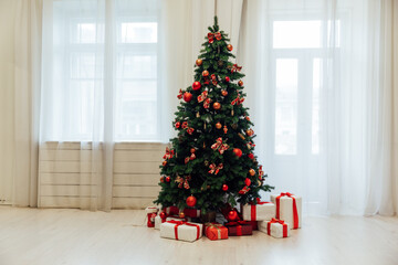 Christmas tree with red gifts in the interior of a room with windows