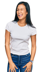 Beautiful hispanic woman wearing casual white tshirt winking looking at the camera with sexy...
