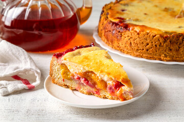 Homemade tart with yellow plums, raspberries and curd cream on a light background
