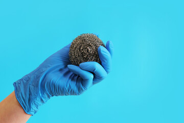 Stainless steel kitchen brush. Barbecue cleaning tools. A hand in a latex blue glove holds a...