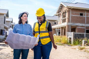 Real estate concept.female engineer, contractor standing, holding blueprints to inspect house construction work from black female contractor for a housing development project.