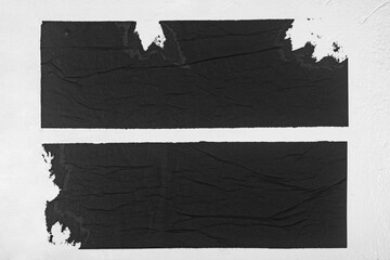 Two strips of black paper on a white background.