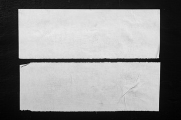 Two strips of white paper on a black background.