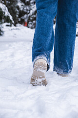 woman legs in winter boots making step in snow