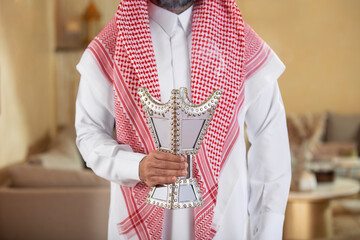 An Arab man holds a censer and perfumes himself with its smoke - obrazy, fototapety, plakaty