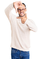 Fototapeta premium Young handsome man wearing casual clothes and glasses smiling making frame with hands and fingers with happy face. creativity and photography concept.