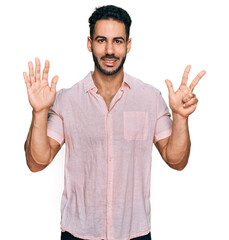 Fototapeta premium Hispanic man with beard wearing casual shirt showing and pointing up with fingers number eight while smiling confident and happy.