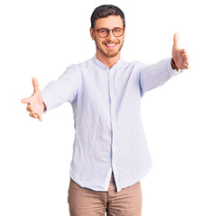 Handsome young man with bear wearing elegant business shirt and glasses looking at the camera smiling with open arms for hug. cheerful expression embracing happiness. - obrazy, fototapety, plakaty