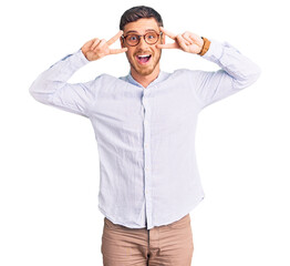 Handsome young man with bear wearing elegant business shirt and glasses doing peace symbol with fingers over face, smiling cheerful showing victory