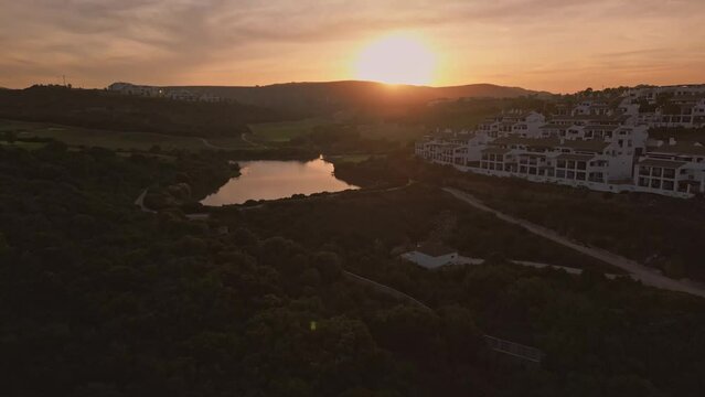 Establishing aerial flying over residential urbanisation neighbourhood. Residential single family houses, lush greenery, beautiful sunset view. Costa del Sol, Spain