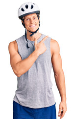 Young handsome man wearing bike helmet cheerful with a smile of face pointing with hand and finger up to the side with happy and natural expression on face