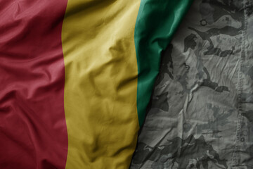 waving flag of guinea on the old khaki texture background. military concept.