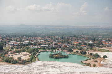 Fototapeta na wymiar Beautiful landscape with calcium travertine terraces, blue pond and sky in Pamukkale, Turkey