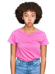 Young hispanic girl wearing casual clothes puffing cheeks with funny face. mouth inflated with air, crazy expression.