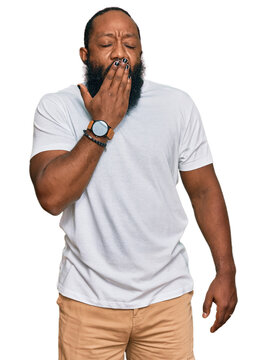 Young african american man wearing casual white tshirt bored yawning tired covering mouth with hand. restless and sleepiness.