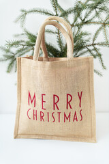This is a photo of a burlap tote bag with Merry Christmas written in red on it, sitting in front of...