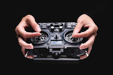 Remote control of FPV racing drone on black background in female hands, close-up