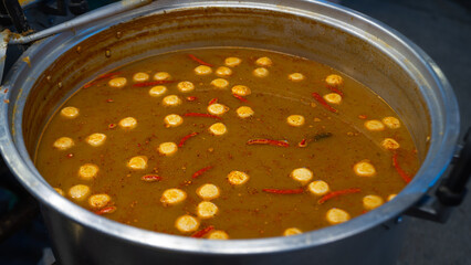 A large pot of curry has curry paste stains on the edge of the pot. shows a decrease in volume Made...