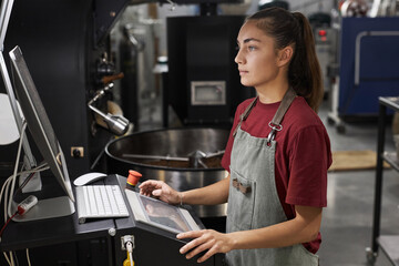 Side view portrait of young woman operating machines at coffee roastery, copy space