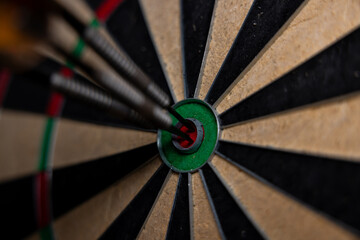 Dart in bulls eye of dartboard with shallow depth of field concept for hitting target.