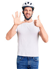 Fototapeta na wymiar Young handsome man wearing bike helmet showing and pointing up with fingers number six while smiling confident and happy.