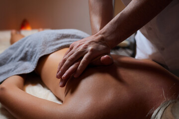 Body massage treatment. Woman having massage in the spa salon. Masseur working on his back.