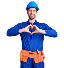 Young handsome man wearing worker uniform and hardhat smiling in love doing heart symbol shape with hands. romantic concept.